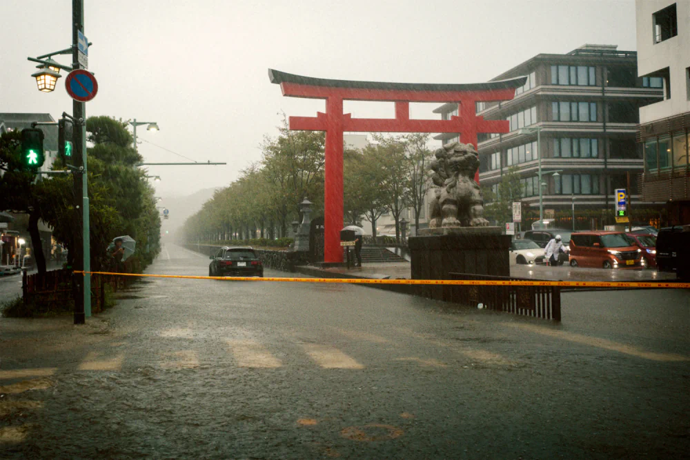 Floodwater covering a road beside a red torii gate in Kamakura during Typhoon No. 15 in September 2025