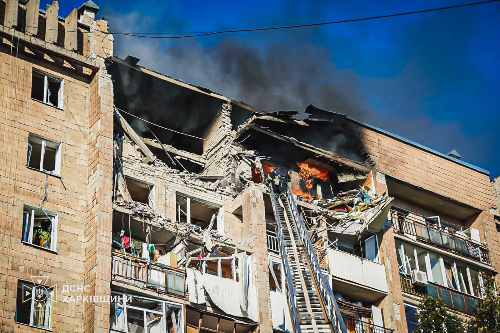 A firefighter on a ladder fights flames in a shattered Kharkiv apartment building after a Kharkiv drone strike — State Emergency Service file photo from an earlier attack on the city