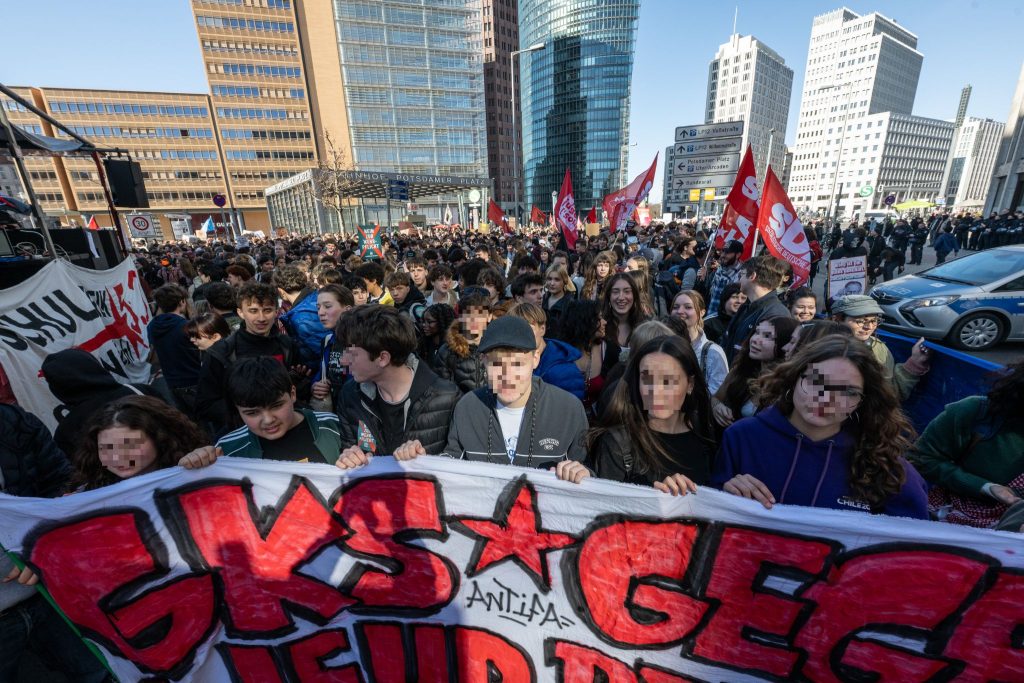 Young protesters marching in Berlin with banners — Germany Halloween cost of living protests coverage