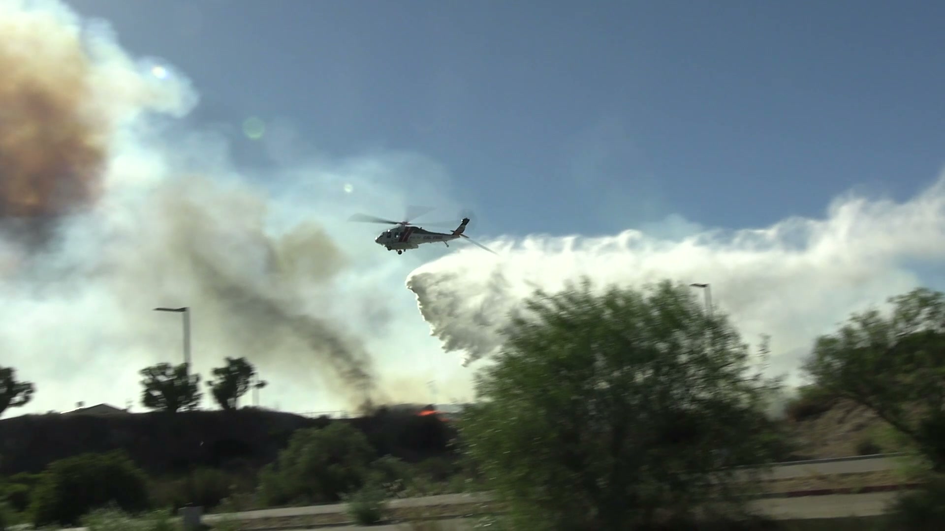 A CAL FIRE helicopter releases water in front of the smoke column from the Henderson Fire at Camp Pendleton on October 15, 2026