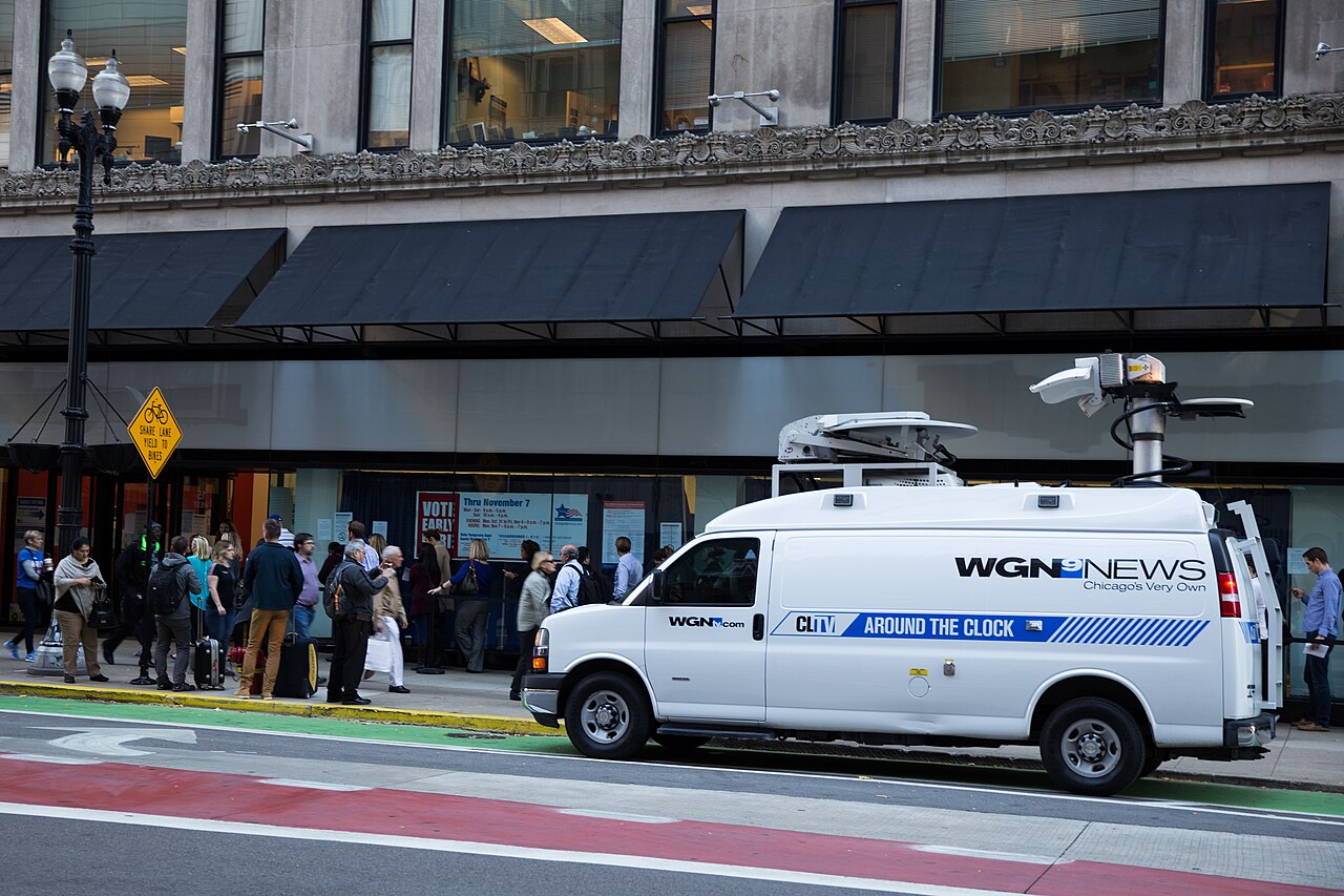 Voters queue outside an early-voting site in downtown Chicago as a television news van stands by