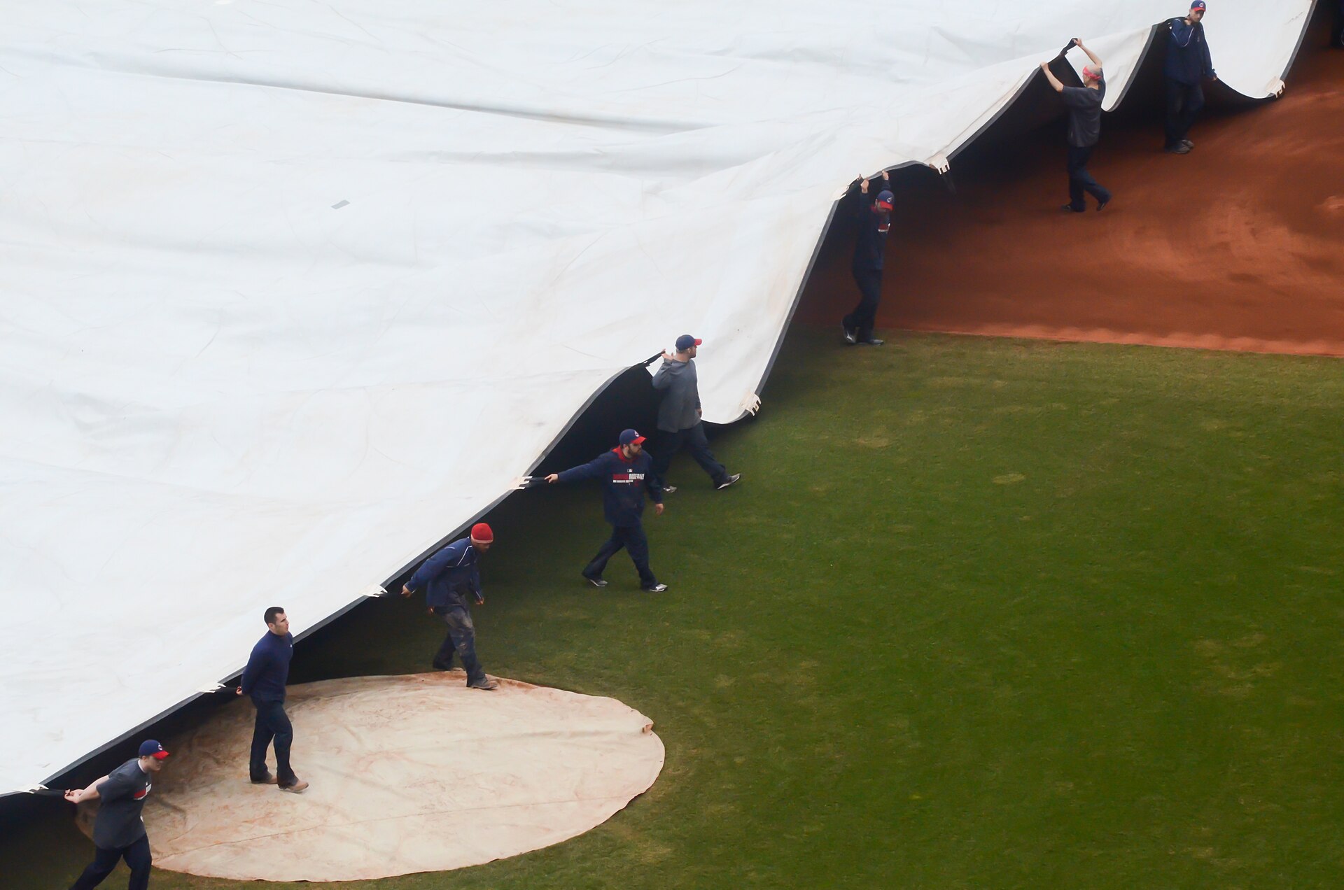 The grounds crew pulls the tarp across the infield at Progressive Field in Cleveland — file photo of the tarp going on, as rain postponed Guardians Rays ALCS Game 4