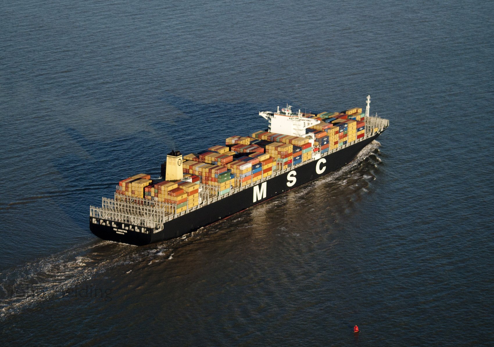 Container ship docked at a container terminal with cranes — Hormuz container shipping file photograph