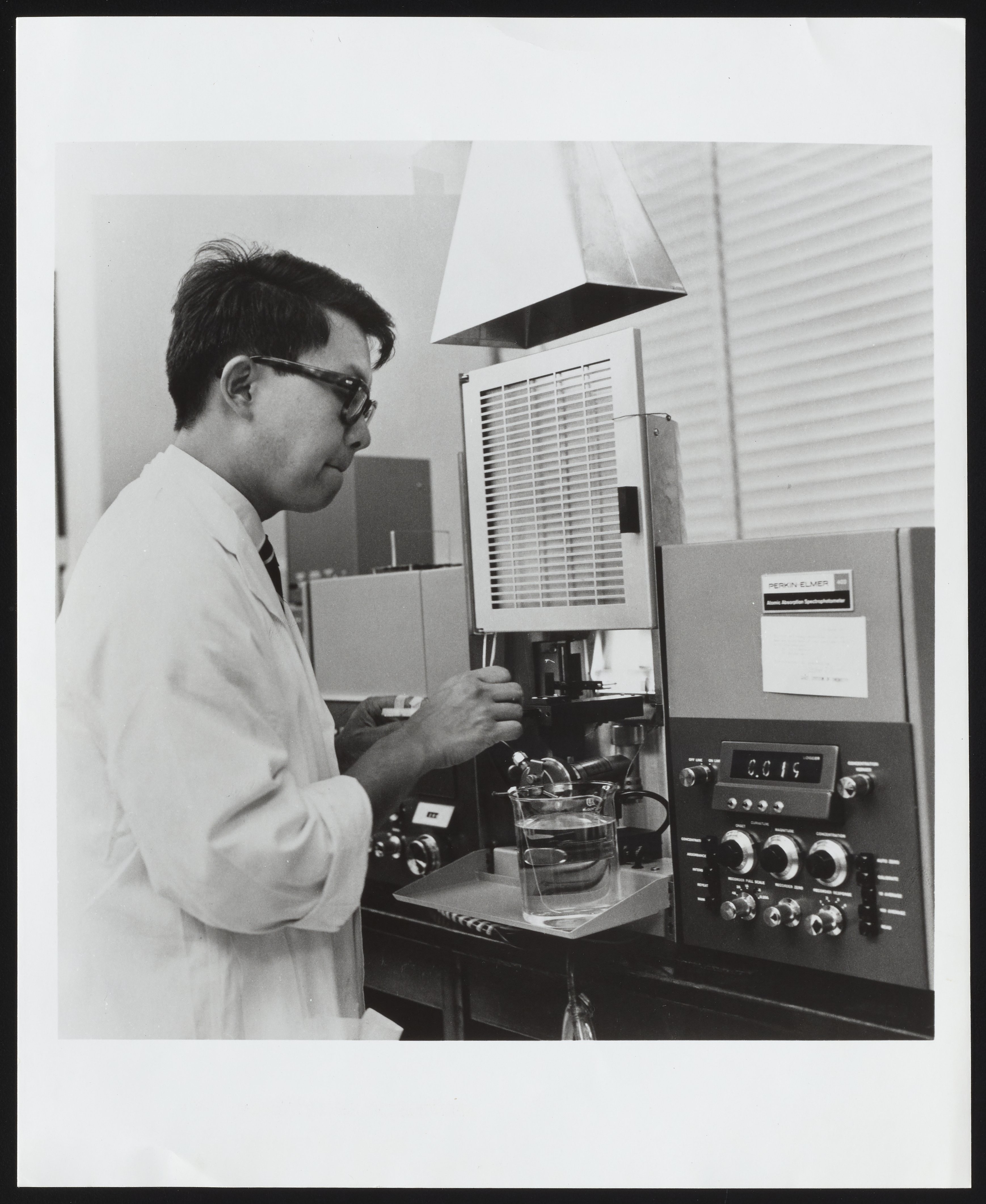 A laboratory chemist using an atomic absorption spectrophotometer to test the lead content of a child's blood sample — blood lead testing is central to the WHO lead poisoning warning