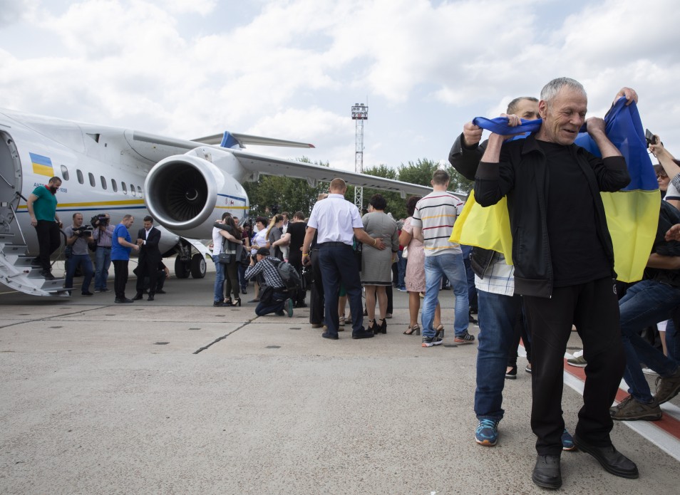 A Ukrainian released from Russian custody holds a Ukrainian flag over his shoulders on the tarmac after arriving home — file photo from an earlier exchange in Kyiv, September 2019