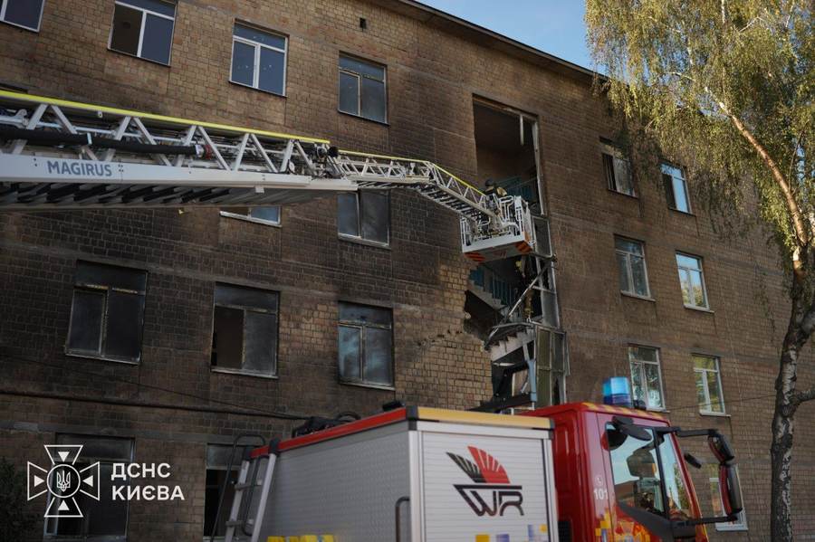 Firefighters inspect the burned facade after a Russian drone hit a Kyiv school in the Solomianskyi district
