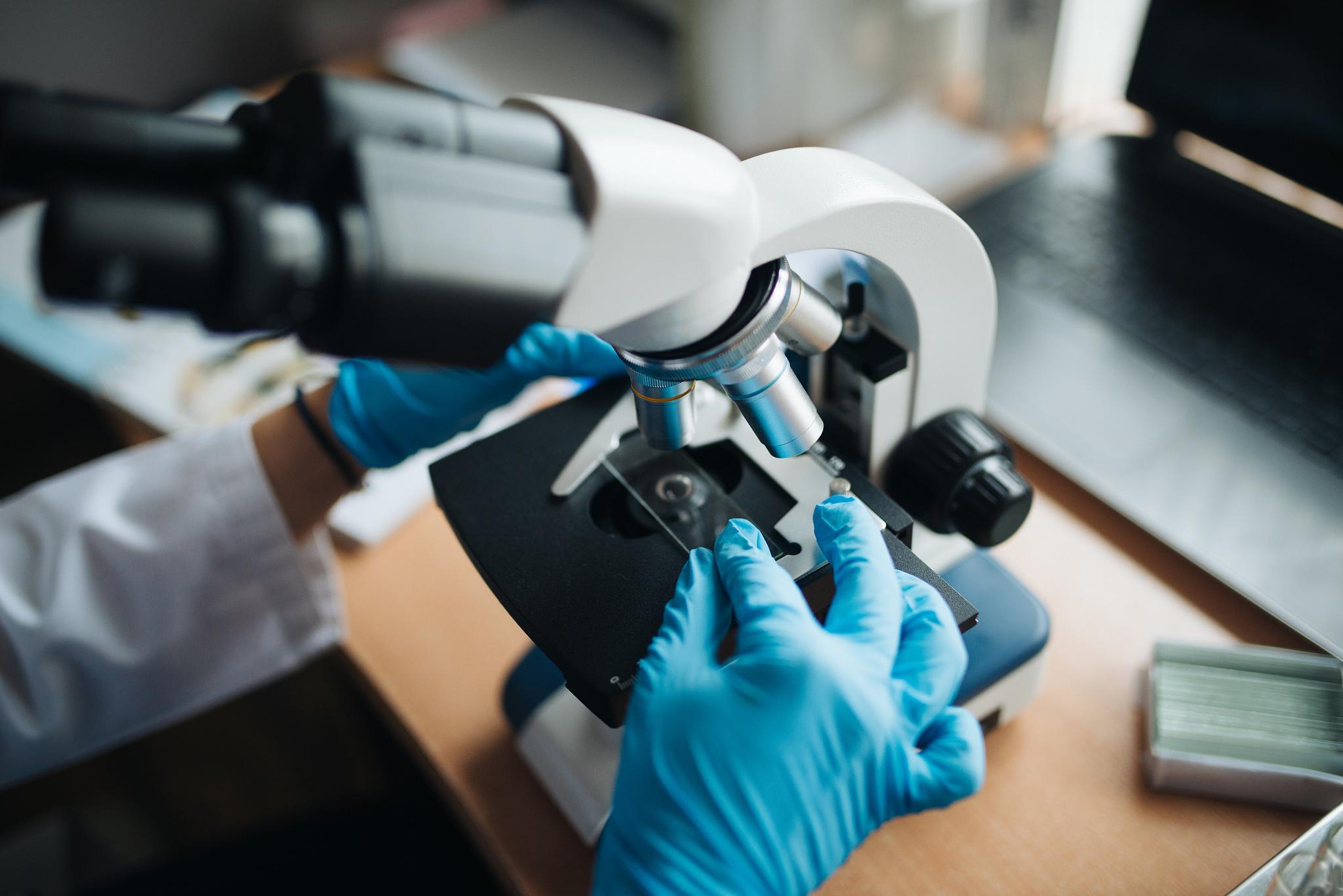 A laboratory technician adjusting a microscope slide in a pharmaceutical research laboratory — retatrutide remains investigational and is not yet FDA-approved