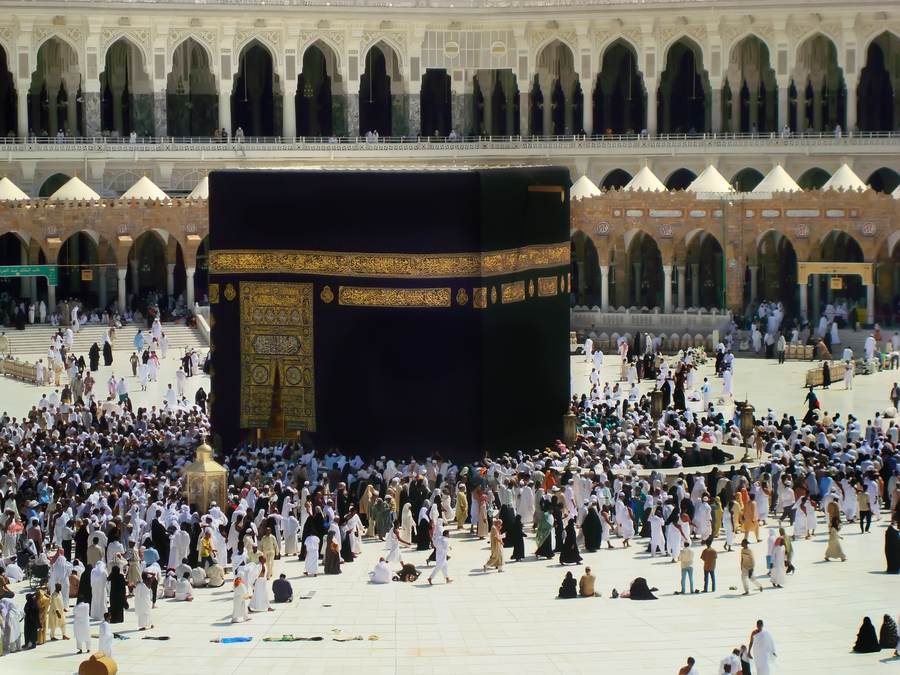 The Kaaba's golden door and black Kiswah cloth with pilgrims in the courtyard of the Grand Mosque