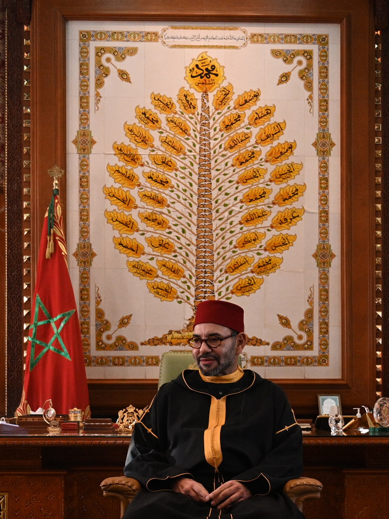King Mohammed VI of Morocco seated beside the Moroccan flag as the country votes in the 2026 legislative elections