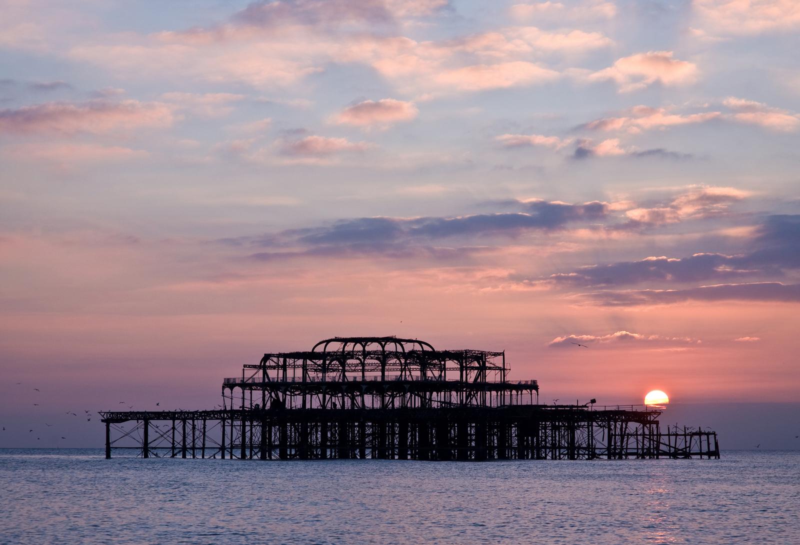 Brighton's derelict West Pier silhouetted against the sea at sunset — part of the pier fell into the sea during Storm Austen