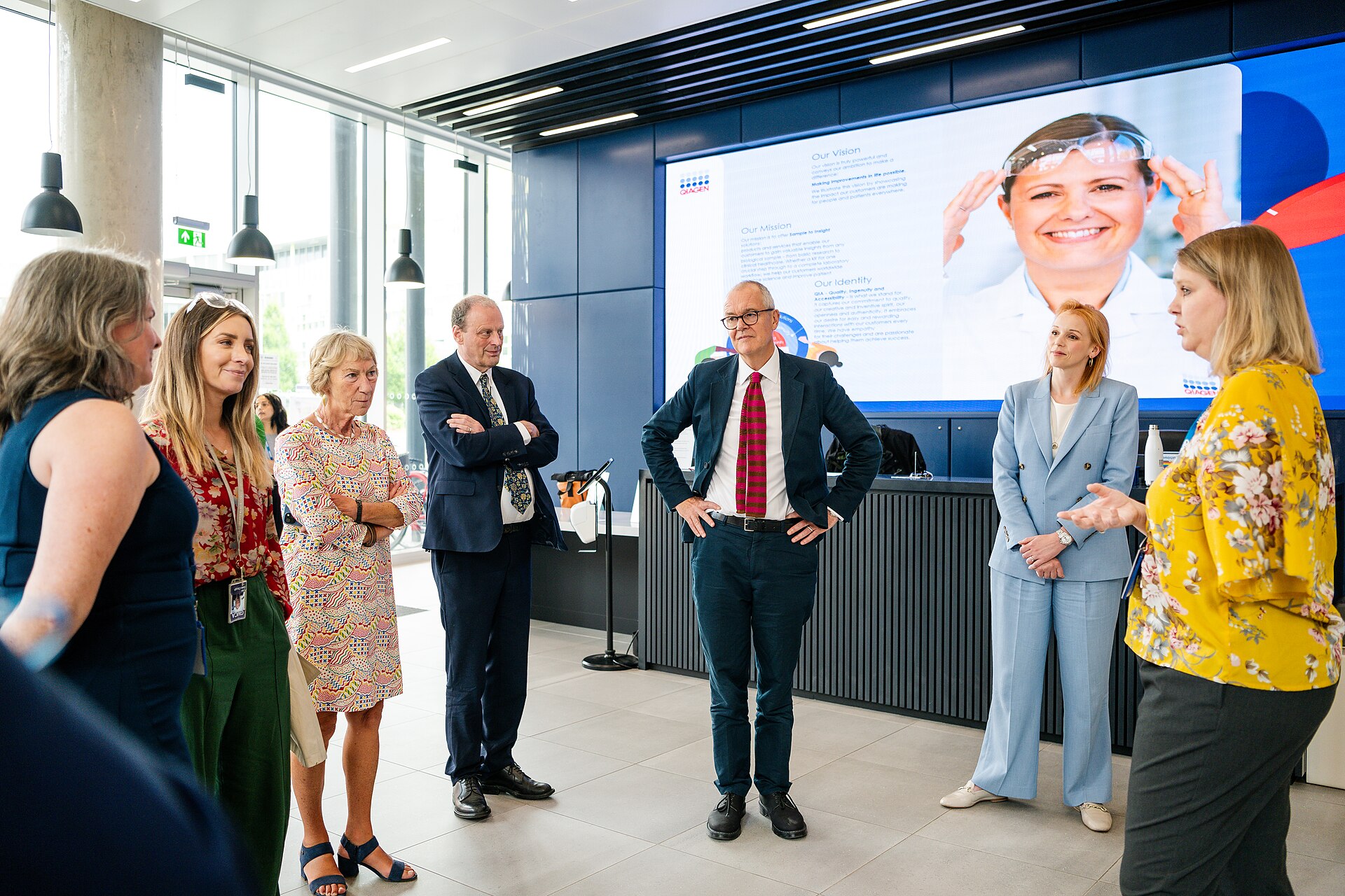 Patrick Vallance visiting a Qiagen facility in front of a Qiagen vision display — EQT buys Qiagen