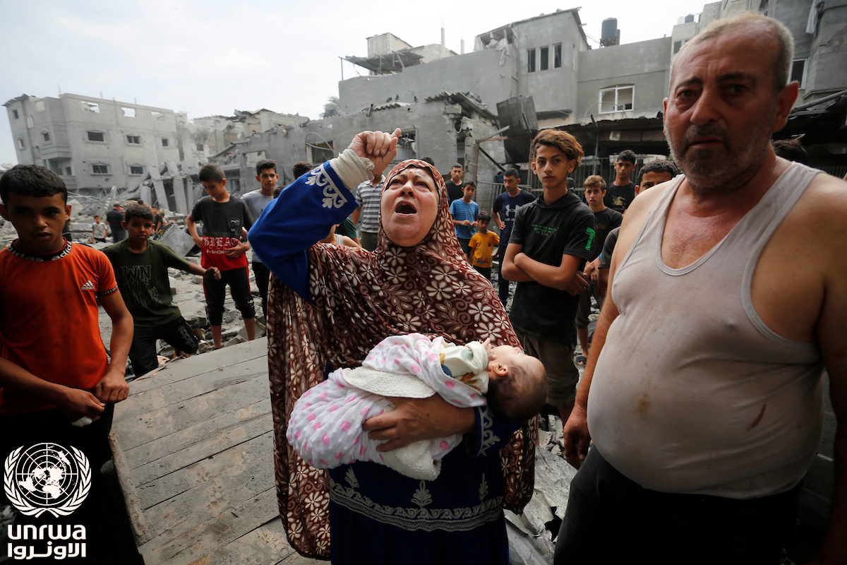Palestinian refugee carries her grandchildren after bombing in Nuseirat camp, Gaza — Gaza teacher killed Israeli strike coverage
