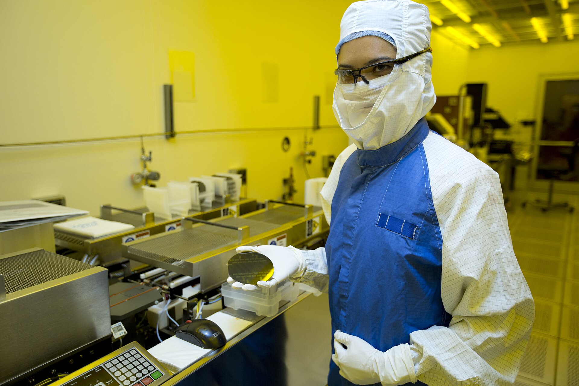 A researcher in cleanroom gear holding a silicon wafer at a semiconductor fabrication facility (file photo) — chip stocks surged at the October 28, 2026 market close on SK Hynix's earnings
