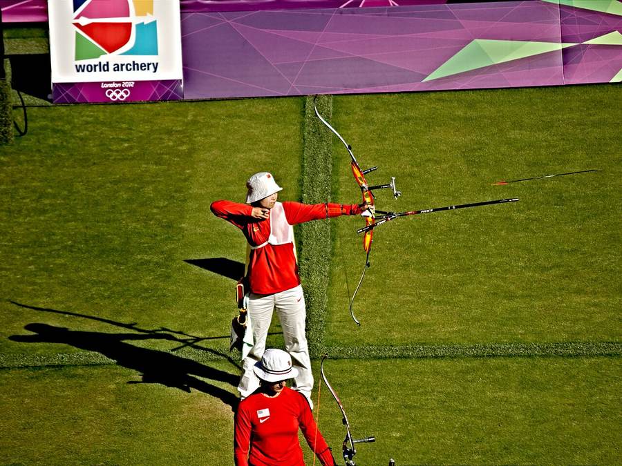 A compound archer releases an arrow in flight — India's mixed team won their Asian Games 2026 final in a 20-19 shoot-off