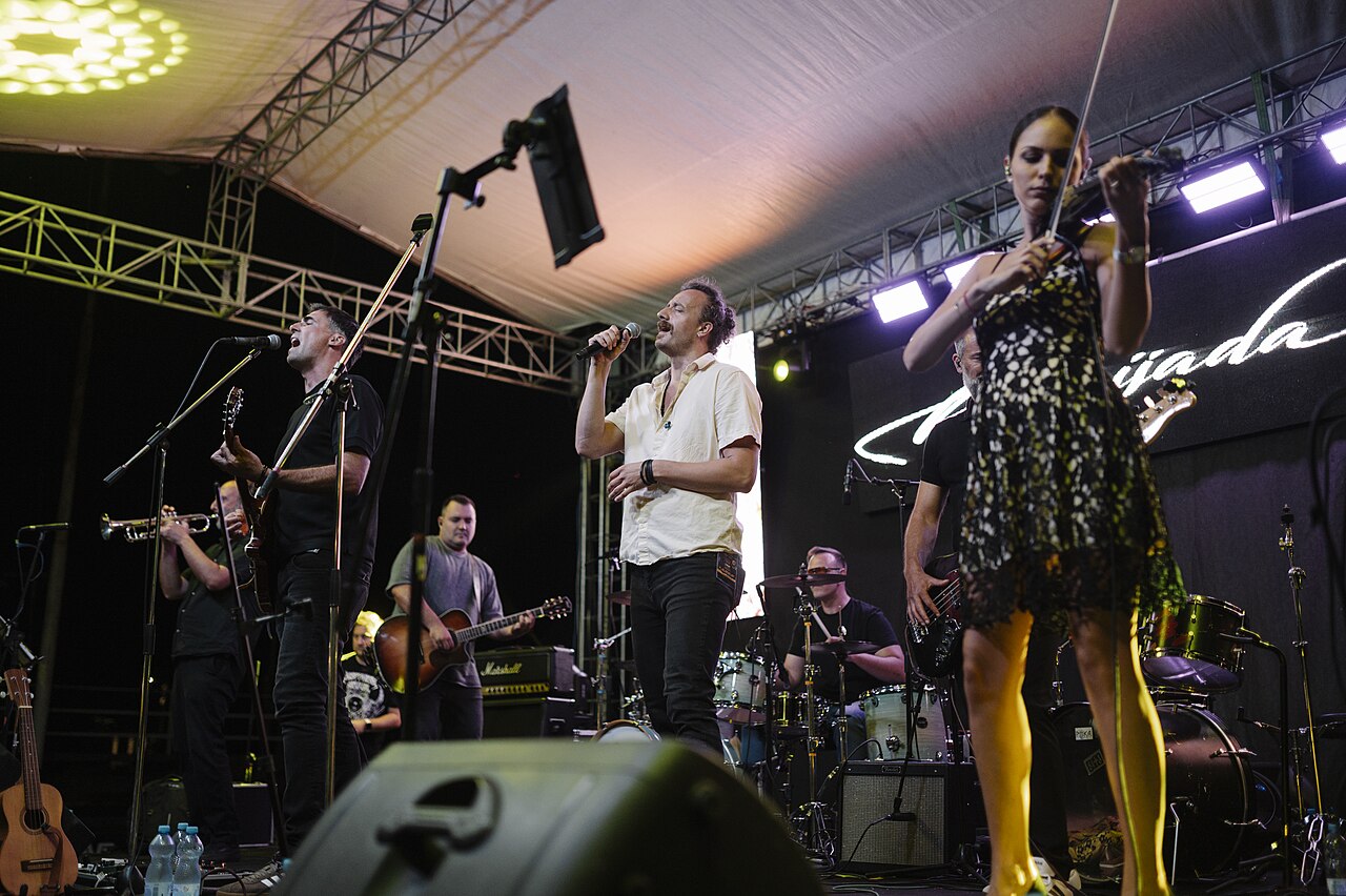 A crowd watching a live performance at an outdoor summer music festival at night