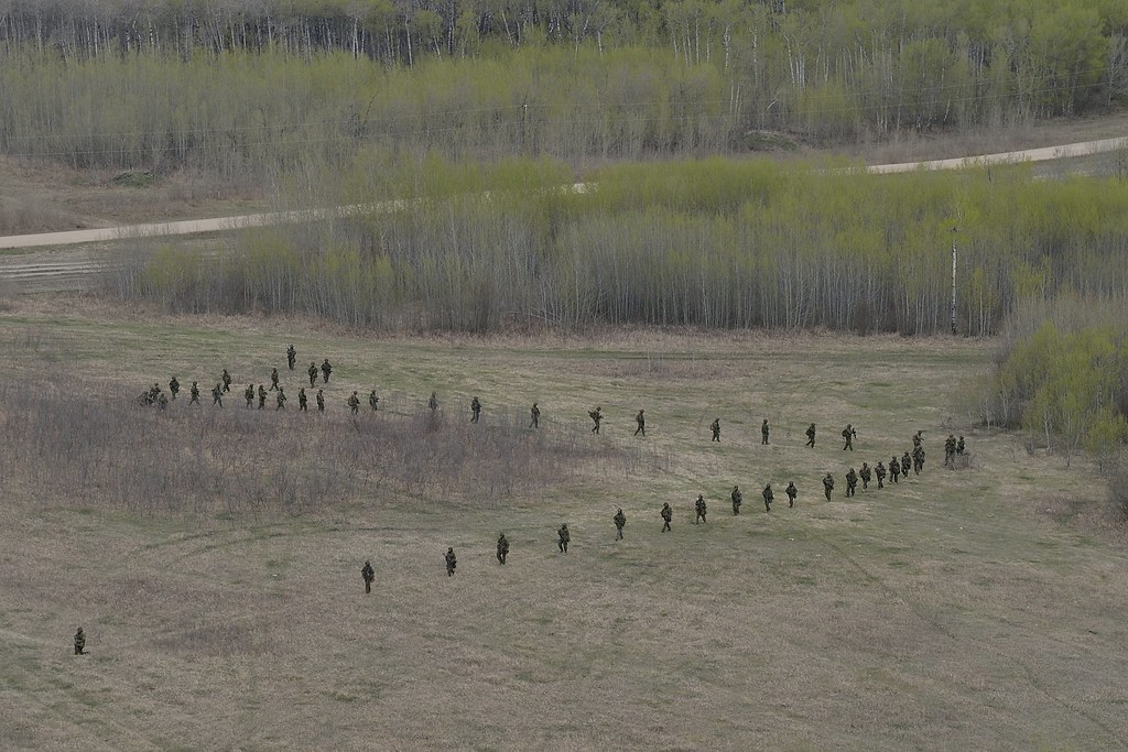 Canadian soldiers advancing across a field during live training at CFB Wainwright, Alberta