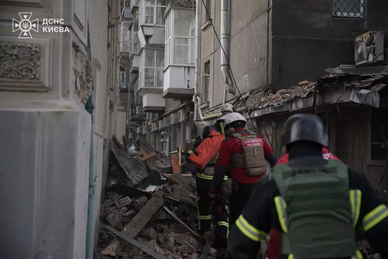 Emergency workers walking through rubble after a drone attack damaged a Kyiv building