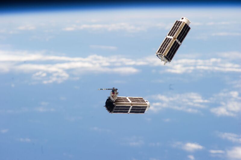 Two Planet Labs Dove satellites deploying from the International Space Station above Earth