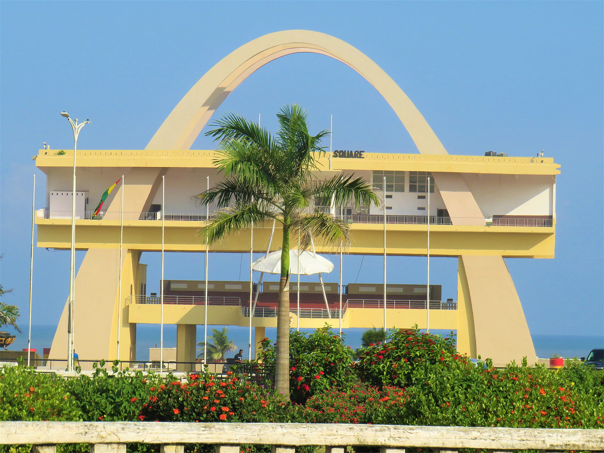 The Independence Arch at Black Star Square in Accra, Ghana, seen across flowering gardens with the Atlantic behind it