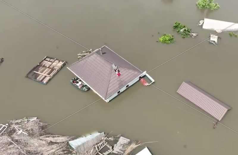 Flooded homes in Oleshky with residents awaiting rescue on a rooftop, June 2023