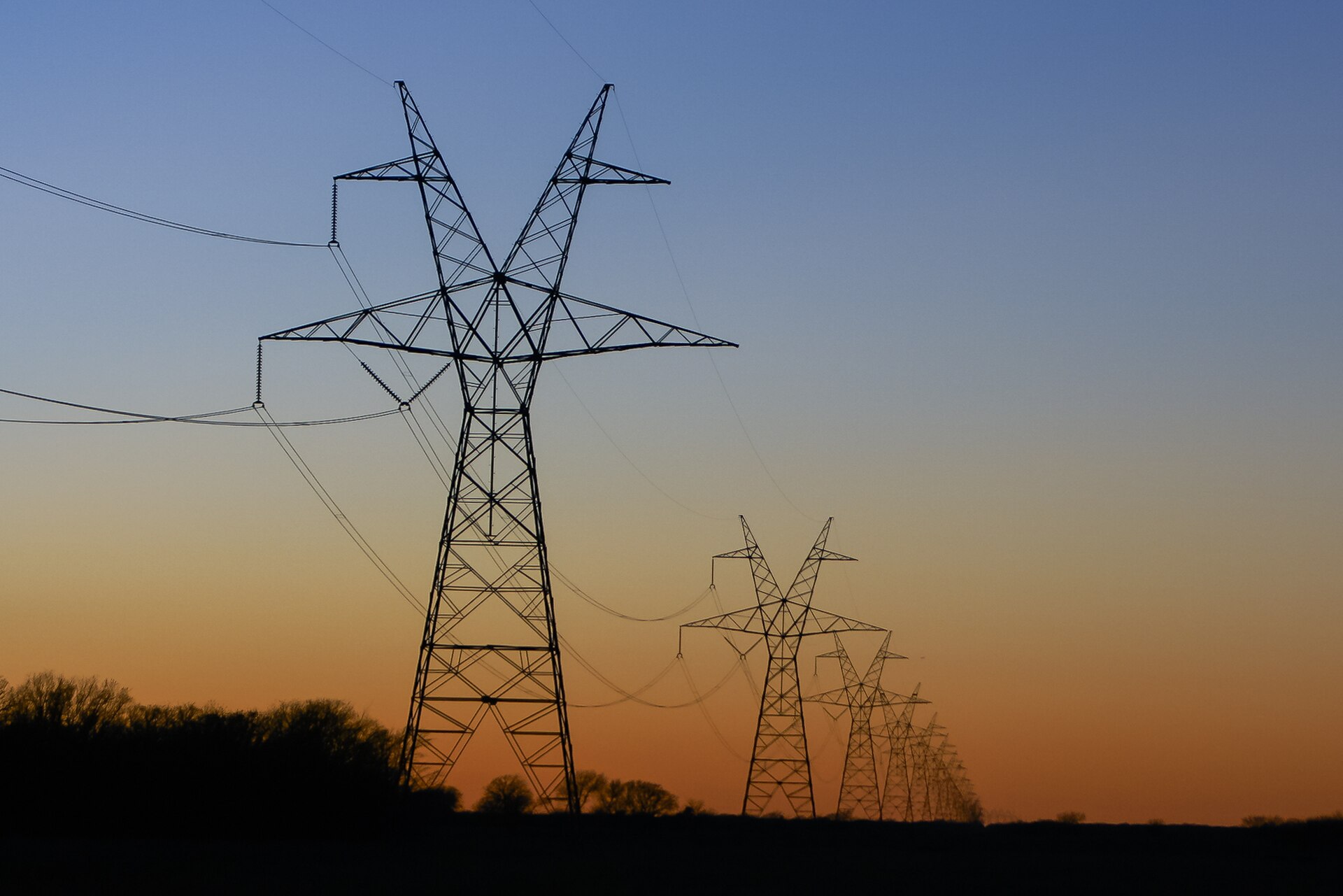 Transmission towers silhouetted against an orange sunset sky in East Texas — file photo
