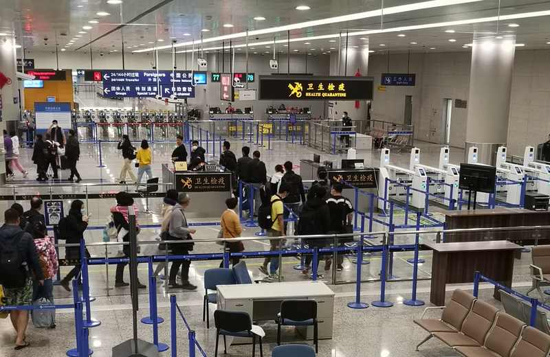 Travelers passing through a health screening area at Shanghai Pudong International Airport