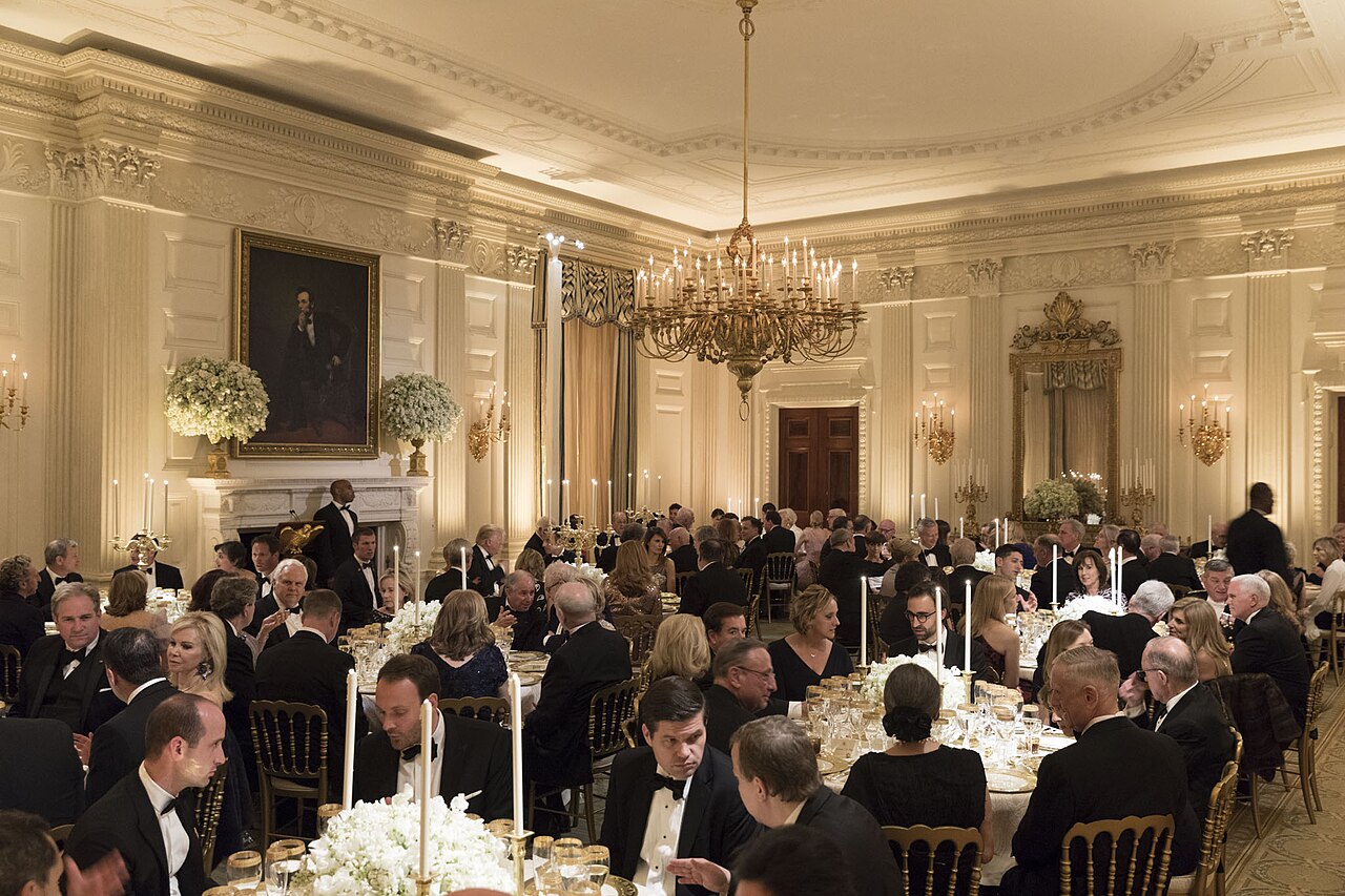 Candlelit White House East Room tables arranged for an earlier state dinner, showing the formal setting used for presidential diplomacy