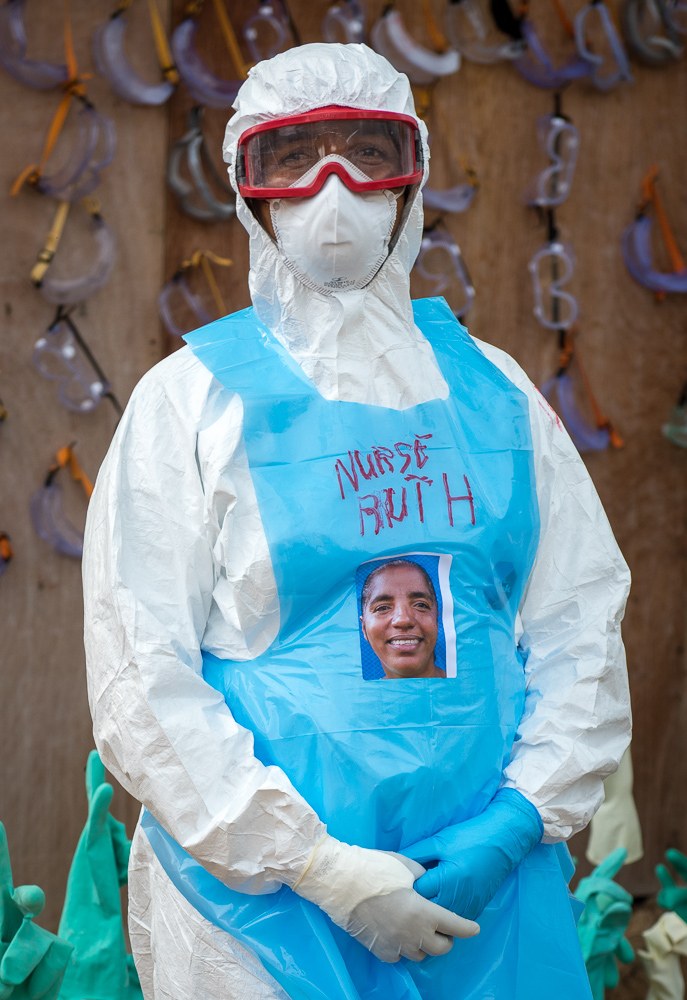 Nurse in full Ebola protective equipment with her photograph pinned to her apron so patients can see her face