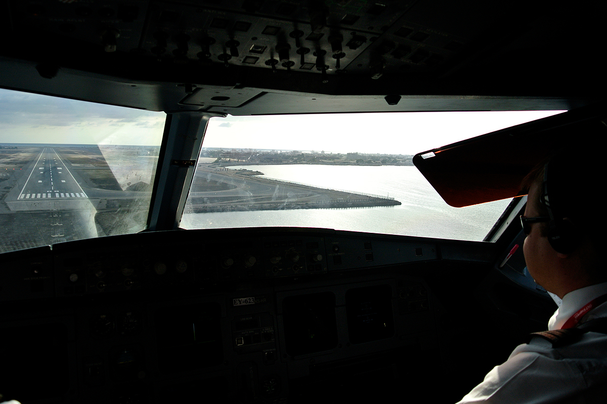 On final approach to Aden International Airport, seen from the cockpit of an East Air Airbus A320, with the runway ahead and the Aden coastline to the right