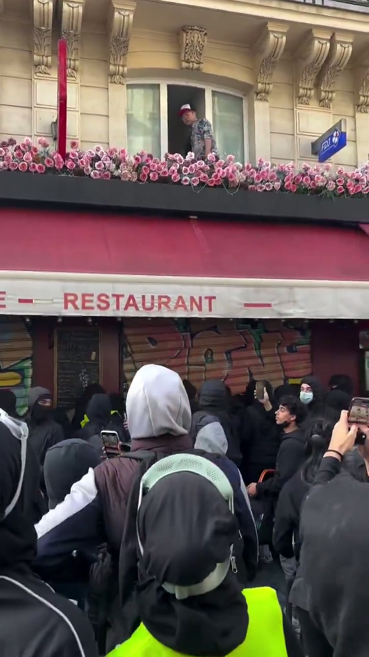 The crowd gathered below the La Barrique restaurant awning on Rue Beaurepaire in Paris during the October 2026 riots