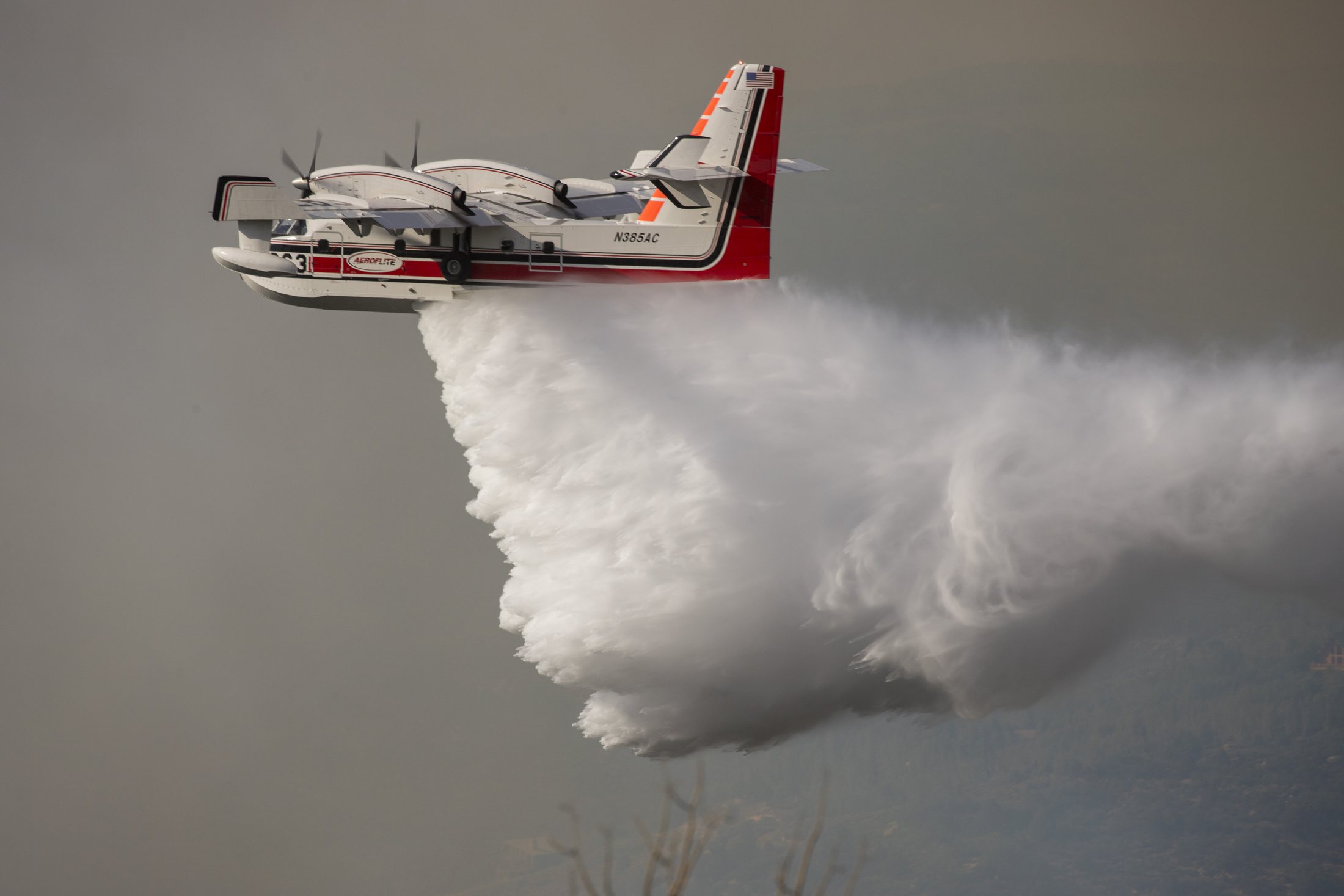 A firefighting water scooper releasing a load during wildfire air operations