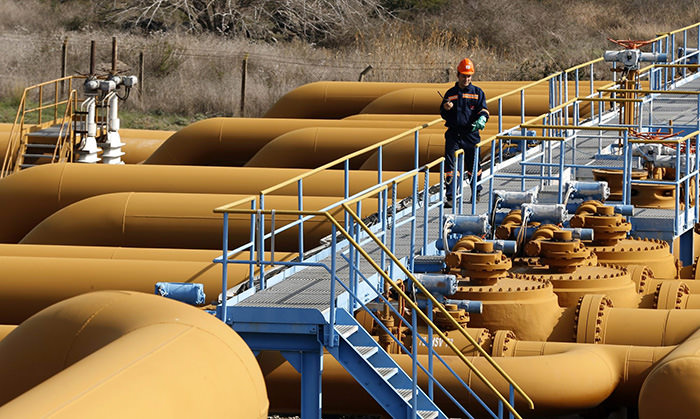 A worker standing above large valves and pipes on the Kirkuk-Ceyhan oil pipeline system
