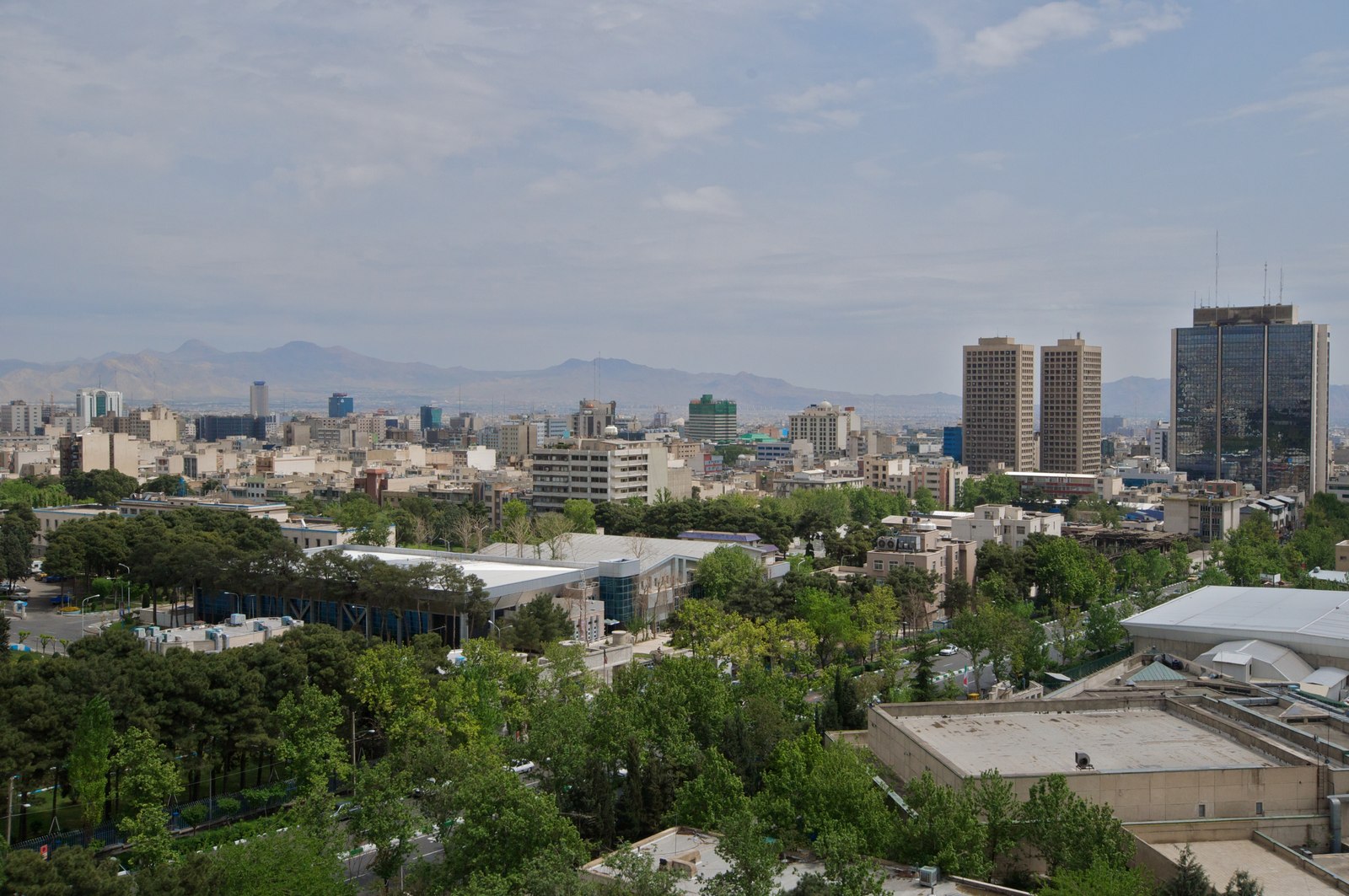 The skyline of southern Tehran seen over Laleh Park, with tower blocks and mountains behind the city