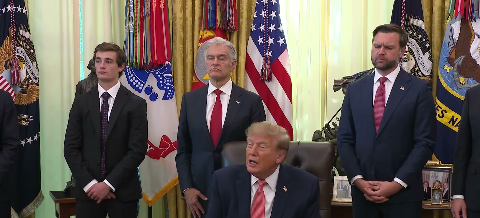 President Trump answering questions in the Oval Office with Nick Shirley, Dr Mehmet Oz and Vice President JD Vance standing behind him