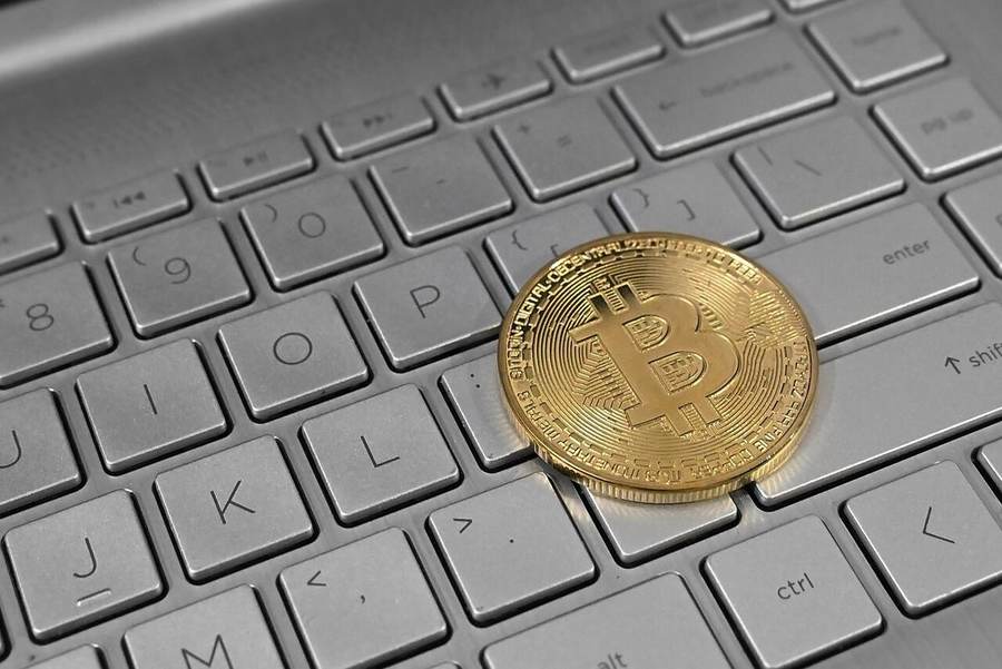 A physical Bitcoin token resting on a laptop keyboard