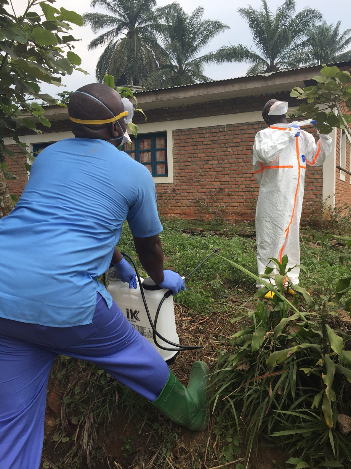 Health worker supervises the careful removal of protective equipment and decontamination spraying at a Congo health centre during Ebola response