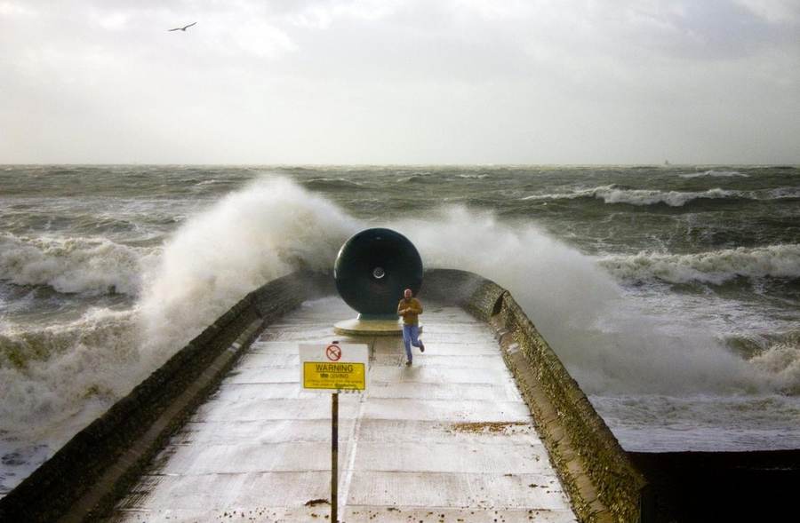 Large storm-driven waves striking a coastal breakwater, illustrating the dangerous surf behind East Coast festival cancellations