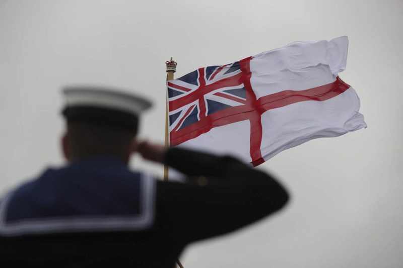 Royal Navy sailor saluting the White Ensign in a file image relevant to the Royal Navy intelligence branch spy allegations