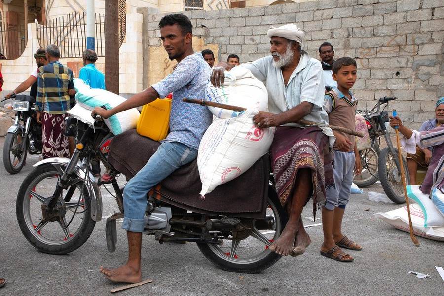 Yemeni families carrying sacks from a World Food Programme distribution during the country's long food insecurity crisis