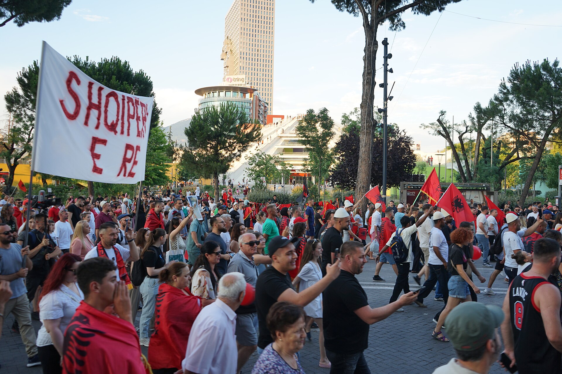 Marchers carry a banner reading 'Shqipëri e Re' (New Albania) through Tirana with the Pyramid of Tirana behind them — Albania protests file photograph