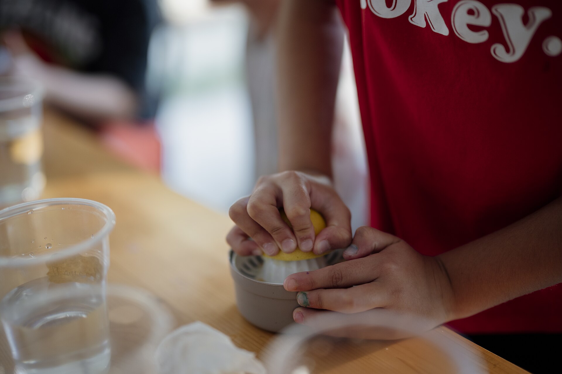 Children learning to cook at a kitchen cooking class, pressing a lemon — the young talent at the heart of the Junior MasterChef Australia format Meghan will help guide