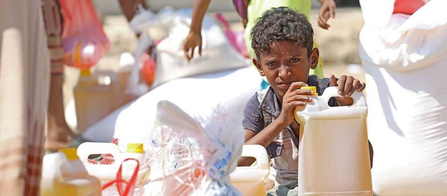 A Yemeni child beside food and cooking-oil aid as the Yemen hunger crisis reaches record levels