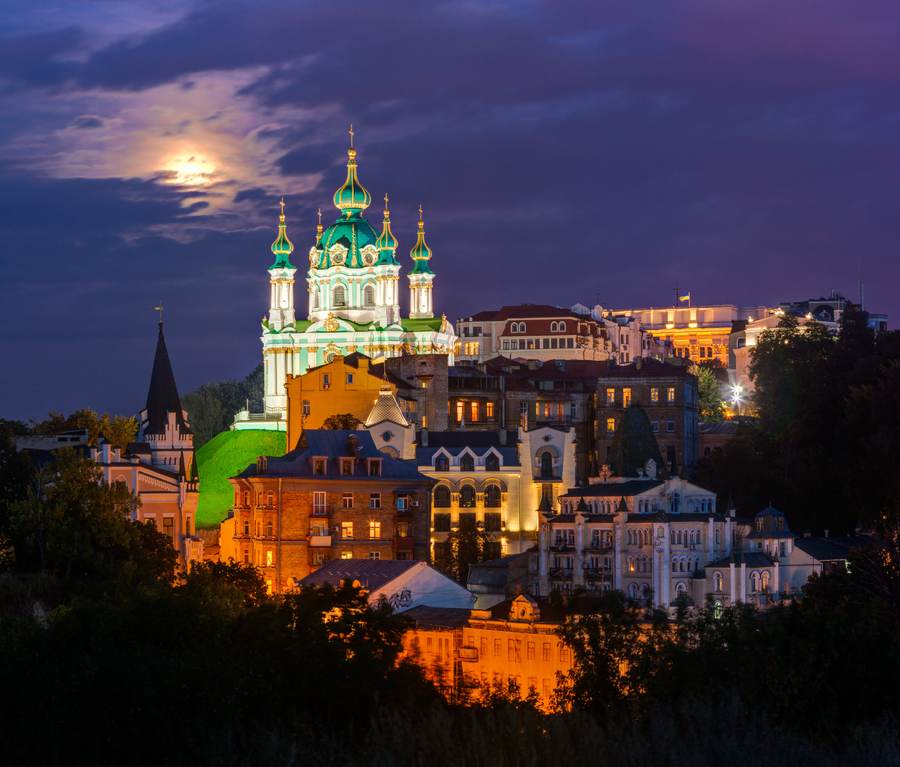 Kyiv skyline and St Andrew’s Church at dusk, photographed from Zamkova Hill