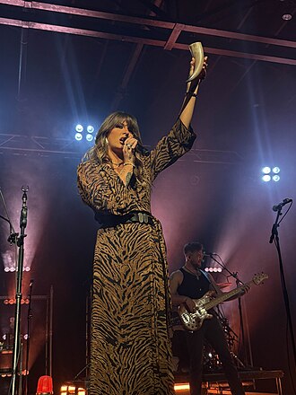 Ella Langley singing onstage and raising a tambourine during a February 2025 concert in Grand Rapids, Michigan