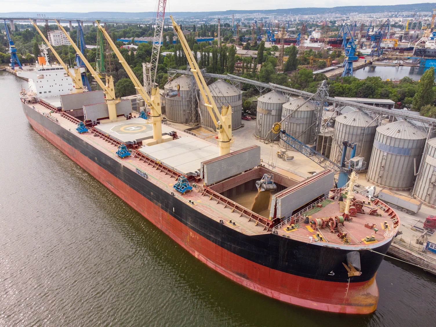 Grain being loaded from port silos into the holds of a sea cargo vessel