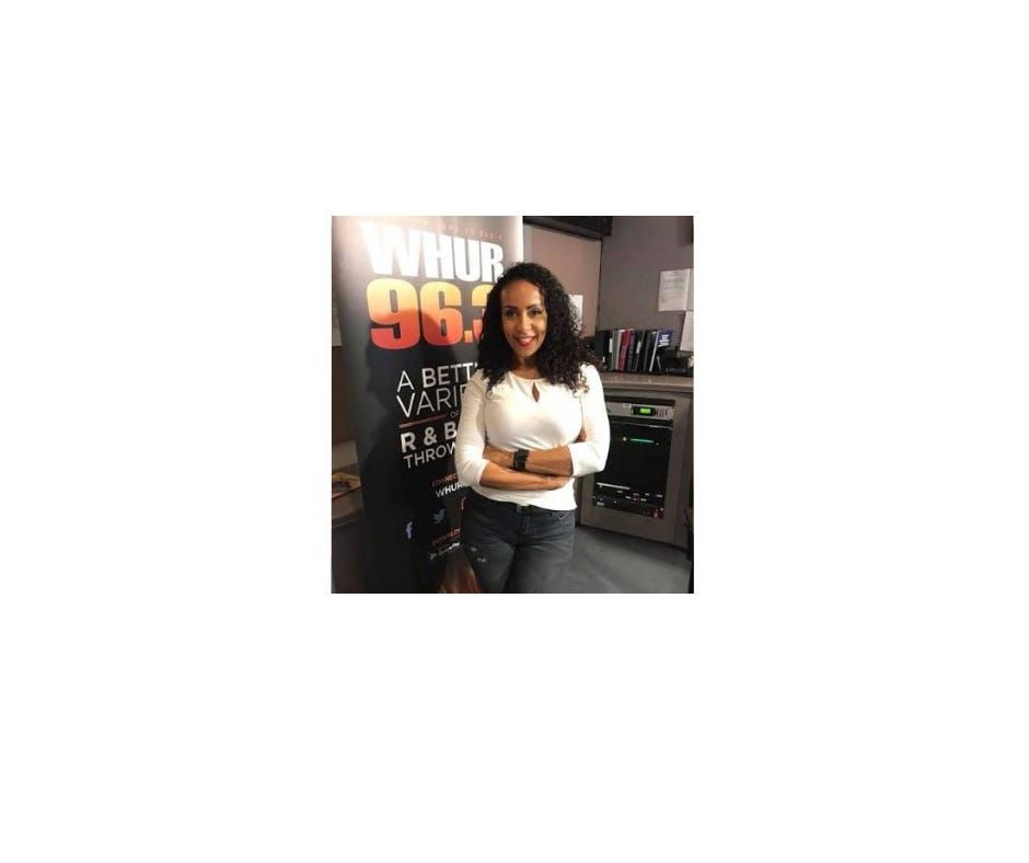 Angela Stribling poses beside a WHUR 96.3 banner in the station's Washington studio — the BET Screen Scene and Jazz Central host and Pillow Talk radio voice died September 26, 2026, after a two-year battle with brain cancer