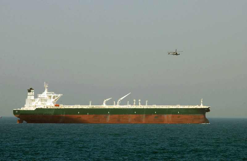 A U.S. Navy SH-60 Seahawk helicopter flies aerial security over the commercial oil tanker AbQaiq, illustrating the war-zone protection now surrounding Red Sea crude shipments after the reported Yanbu port attack of October 2026.