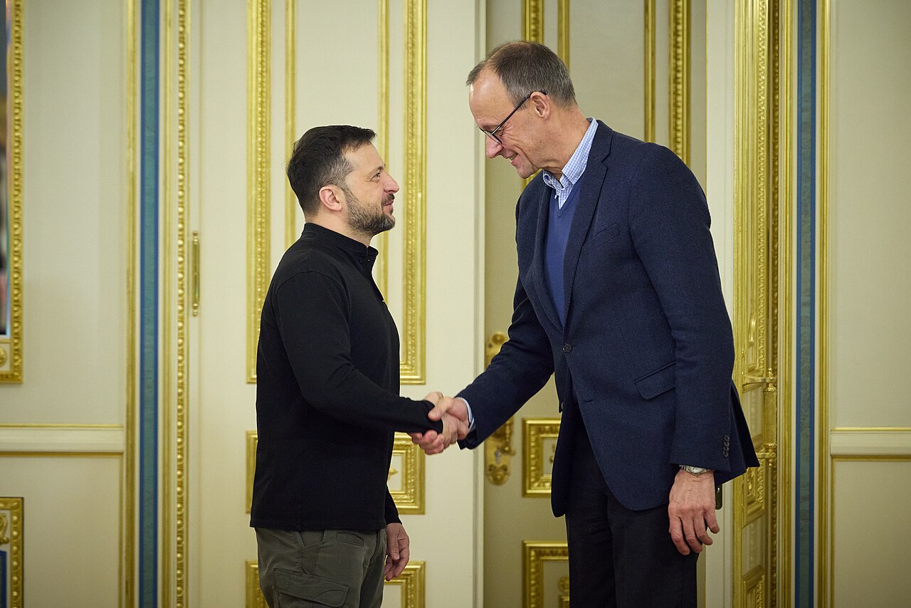 Zelenskyy Trump capitulate interview subject Volodymyr Zelenskyy shaking hands with Friedrich Merz in Kyiv