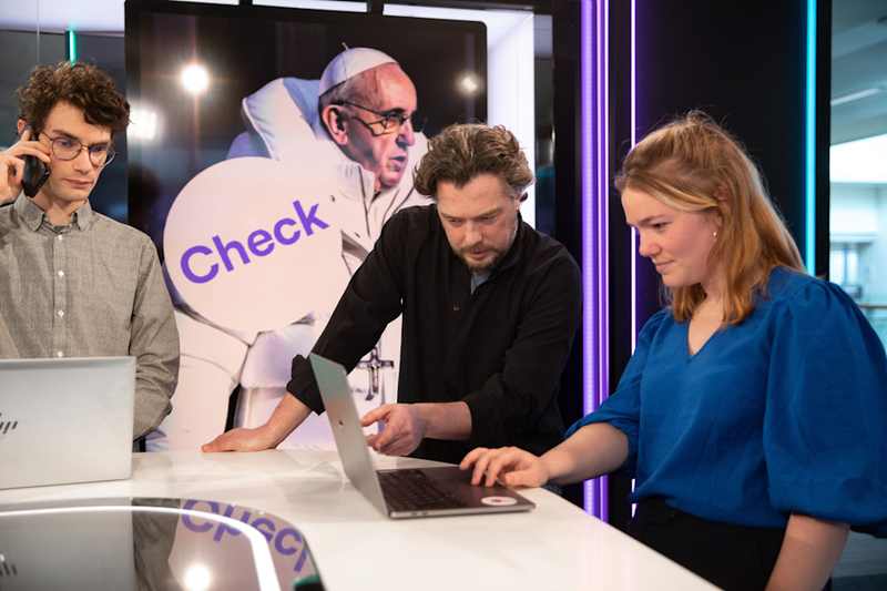 Journalists working at laptops during a fact-checking session, a key use case for an AI watermark detector