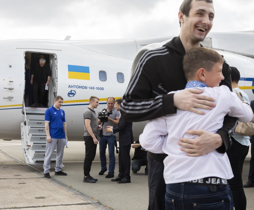 A Ukrainian released in a prisoner exchange embraces a young boy beside a Ukrainian government aircraft after returning home — file photo from an earlier exchange in Kyiv, September 2019